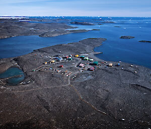 Aerial of red, green and blue station buildings on a rocky, ice-free headland