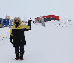 Woman waves to the camera in the snow in Antarctica