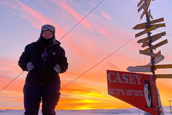Woman stands next to a Casey signpost in the snow