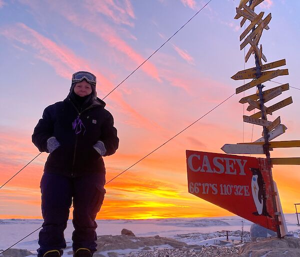 Woman stands next to a Casey signpost in the snow