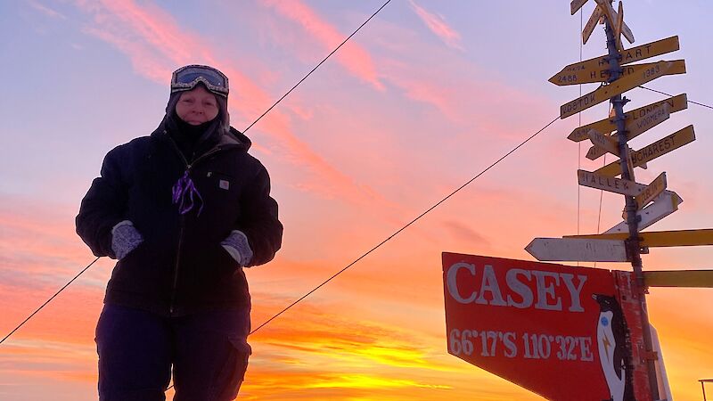 Woman stands next to a Casey signpost in the snow