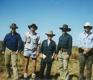 A group of people stand together in a line in the Australian desert