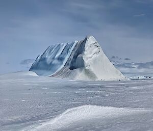 A pyramid shaped iceberg in the middle of a snowy landscape