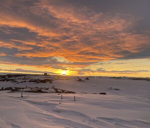 A snowy scene with a orange sunset