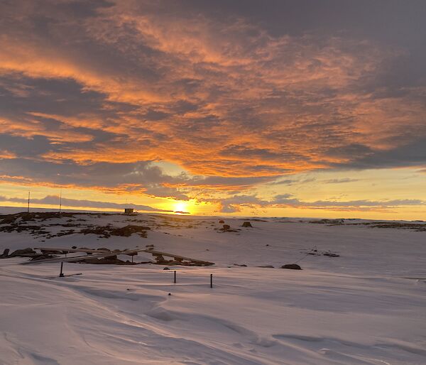 A snowy scene with a orange sunset