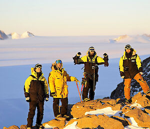 Four people stand on mountain surrounded by ice sheet