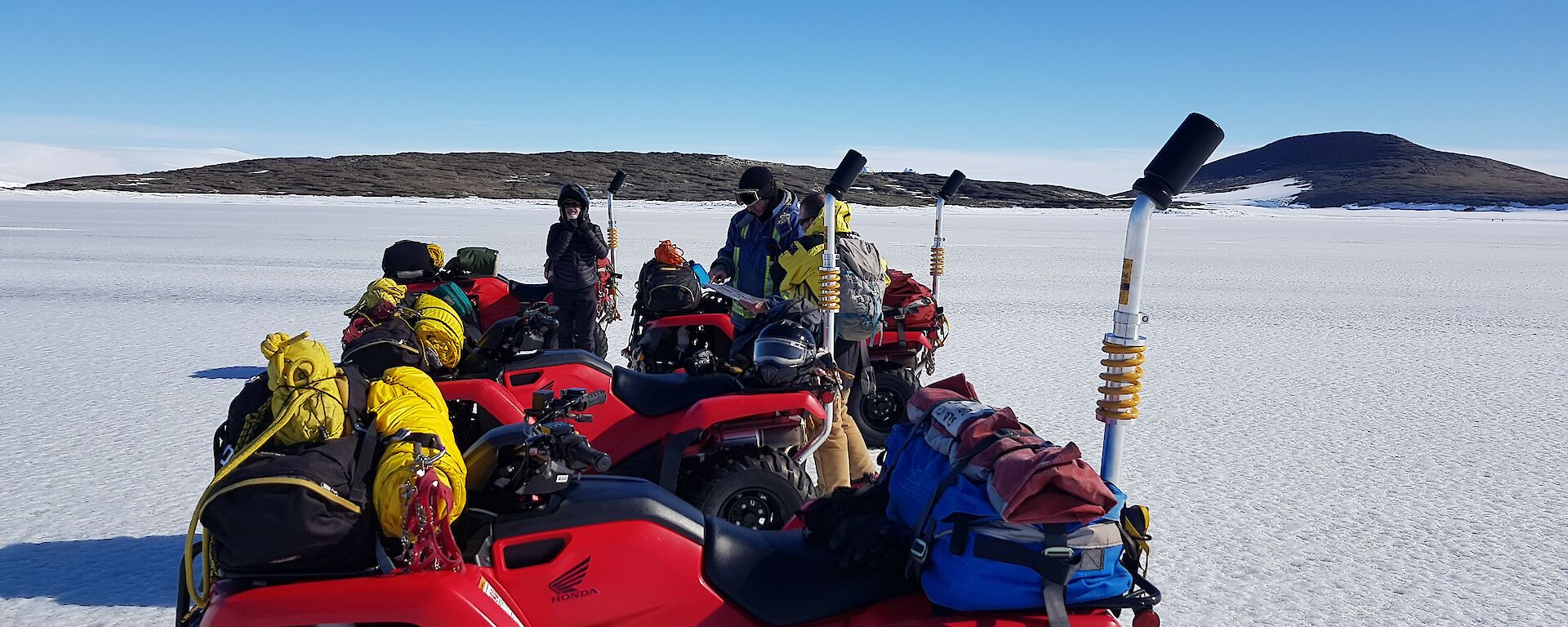 Expeditioners standing beside quad bikes in the snow