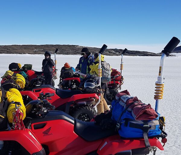 Expeditioners standing beside quad bikes in the snow
