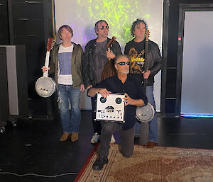 four men with musical instruments in recording studio