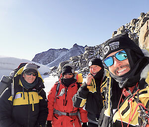 group in bright sunlight at base of rocky peaks