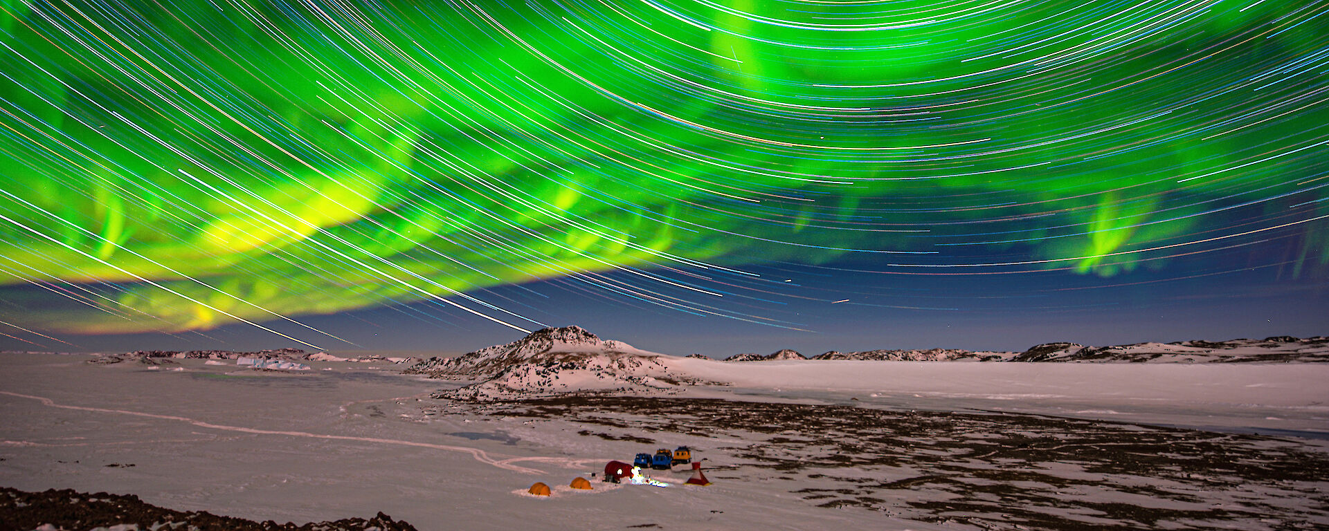 star trails and aurora over icy plain in twilight