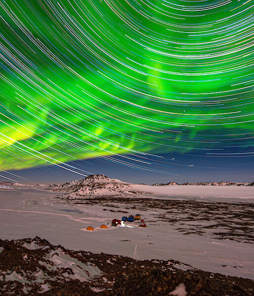 star trails and aurora over icy plain in twilight
