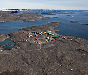 Rocky landscape with small multicolored buildings surrounded by blue water a