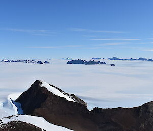 A view from the top of a mountain across a snowy landscape with mountains visible