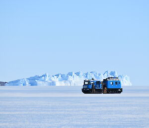 A blue Hagglund on the ice with an iceberg in the background