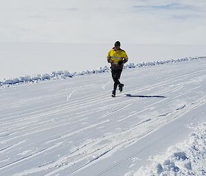 Runner in a bright yellow shirt. Snow on the ground in the background.