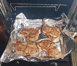 An oven tray with four large cooked steaks