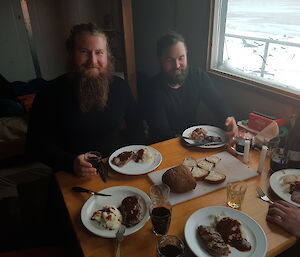 Expeditioners sitting at the hut table eating steak diners