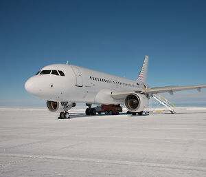 large white plane sitting on ice runway under clear sky