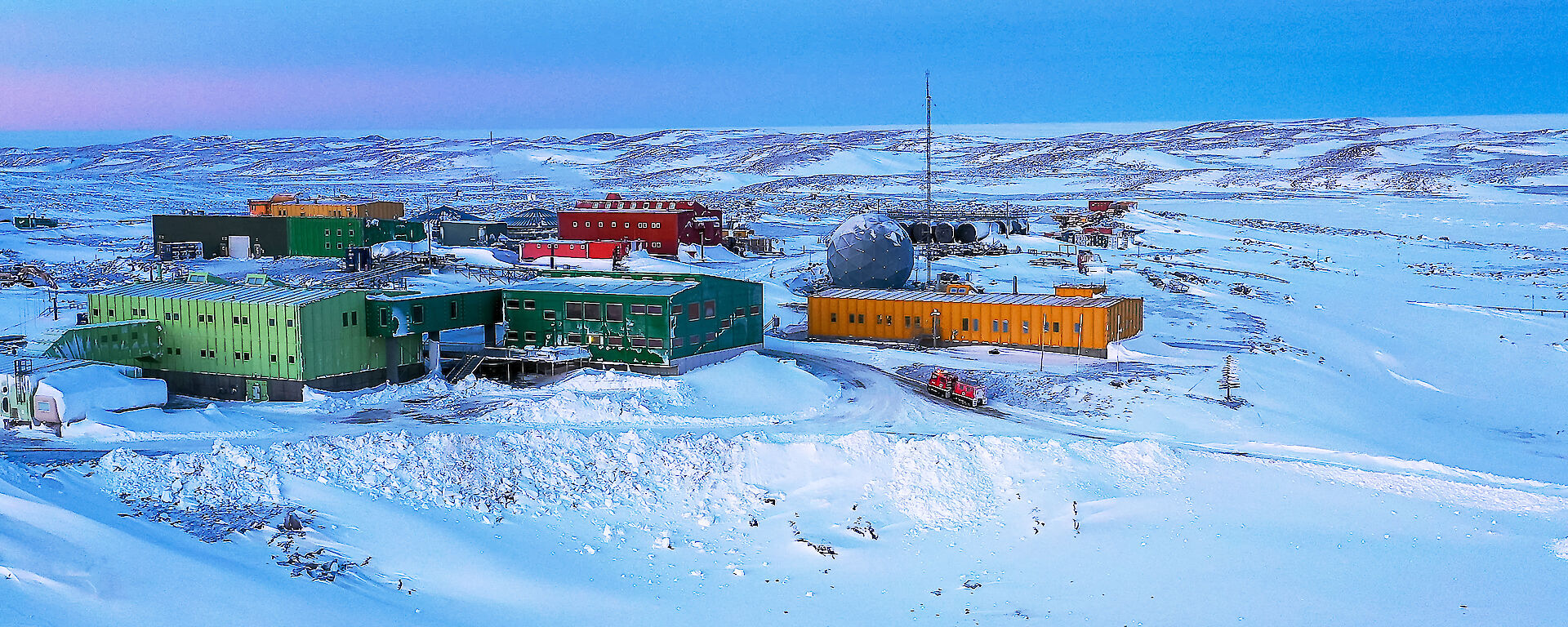 Brightly coloured buildings in snowy landscape under a clear sky