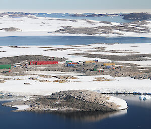 bright buildings set among rock, snow and sea in Antarctica