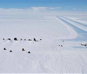 Aerial view of icy runway with parked plane, buildings