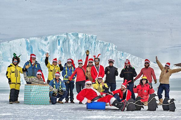 Expeditioners in christmas outfits and santa hats gathered on the ice to wish everyone merry Christmas