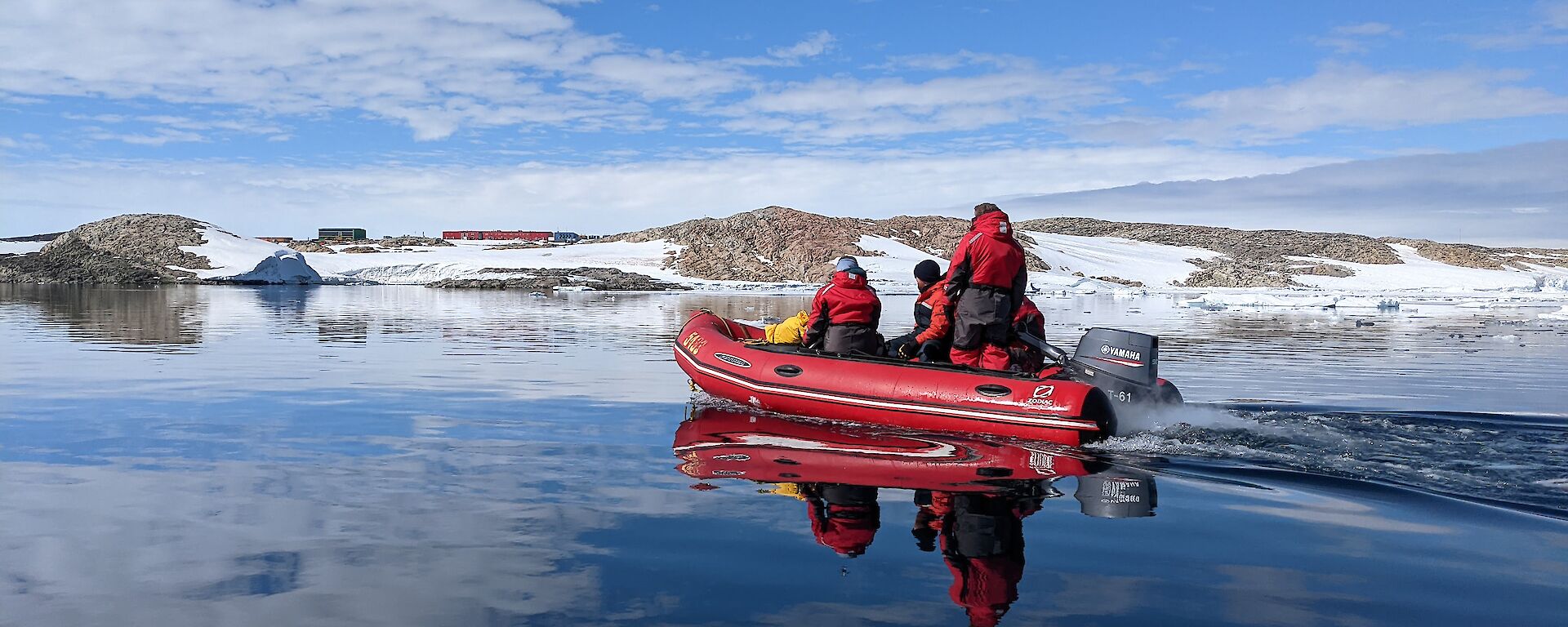 Inflatable boat with expeditioners. Still water conditions. Station in the background.