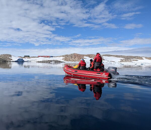 Inflatable boat with expeditioners. Still water conditions. Station in the background.