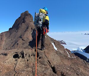 Mountain climber attached to a rope at the top of the mountain looking down towards the ground