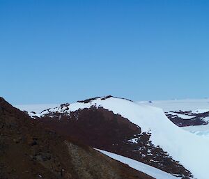 Looking across the mountain tops, two tiny figures can be seen on the top of one of the peaks.