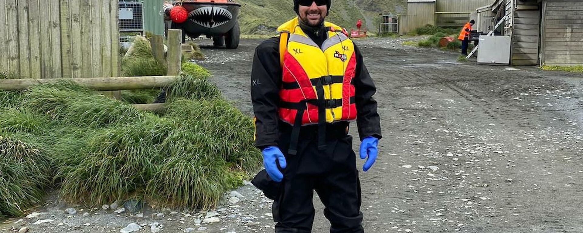 Jamie standing in front of the lark in a dry suit and life jacket