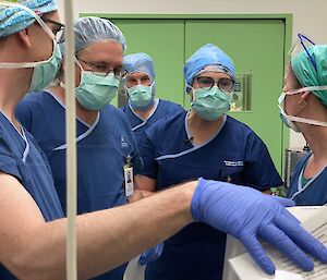 Group of people in scrubs in the operating theatre following instructions