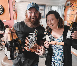 Troy and Alana holding their penguin awards and sparkling wine bottles