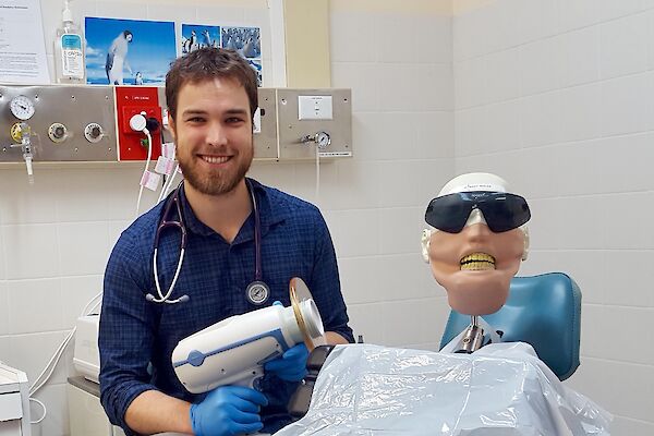 doctor sits next to dental dummy