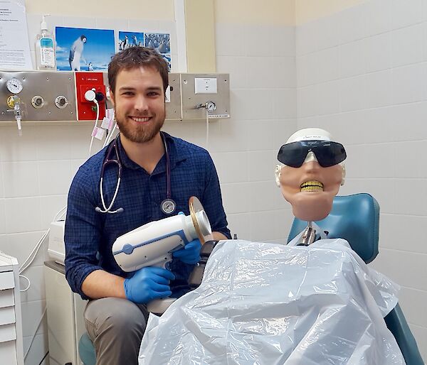 doctor sits next to dental dummy