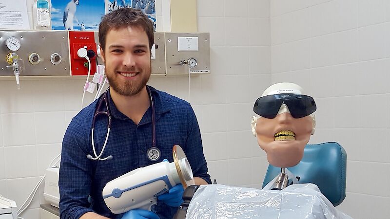 doctor sits next to dental dummy