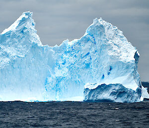 A large blue iceberg floating in the sea