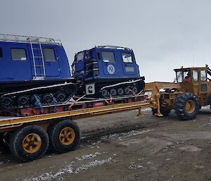 Blue Hägglunds vehicle on the back of a skid steer and tray.