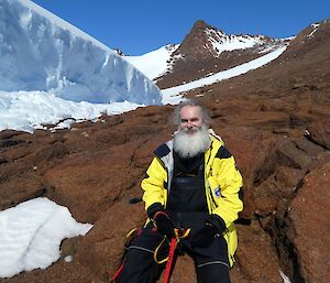 An expedition sits on a rocks at the side of a wind scour smiling to camera