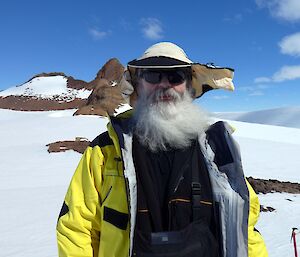 An expeditioner with full grey beard and sunglasses on sporting a floppy straw hat
