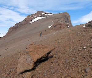 An expeditioner climbing the rocky ridge of Mount Parsons