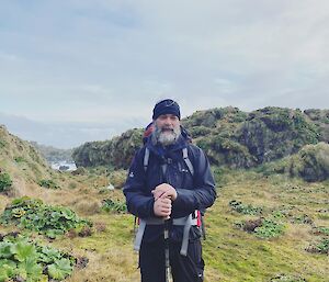 Expeditioner standing at the top of a hill in his hiking gear, smiling to camera