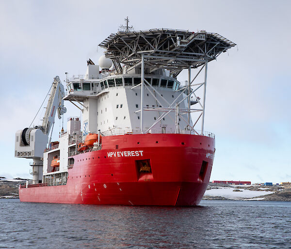 large red and white ship with helipad next to the ice