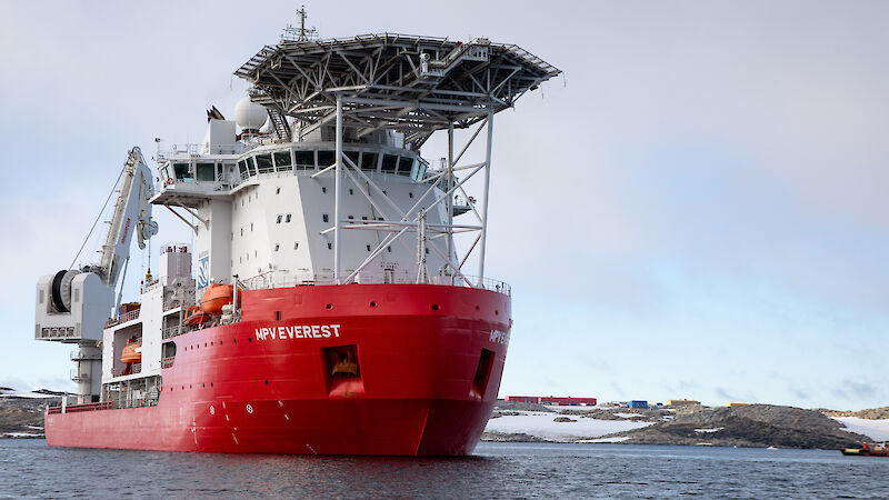 large red and white ship with helipad next to the ice