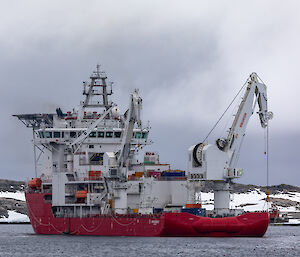 large red and white ship with helipad next to the ice