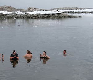 Five expeditioners standing up to their necks chests in icy sea