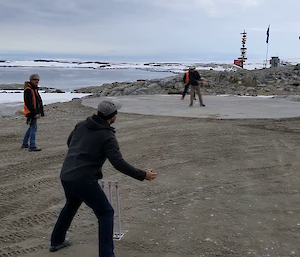 Expeditioners playing cricket with the icy sea in the background