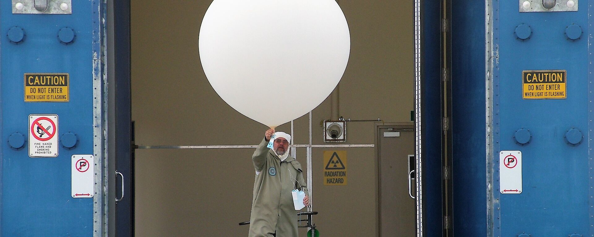 man in protective gear with large white balloon and ozone sonde