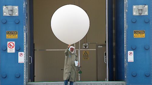 man in protective gear with large white balloon and ozone sonde